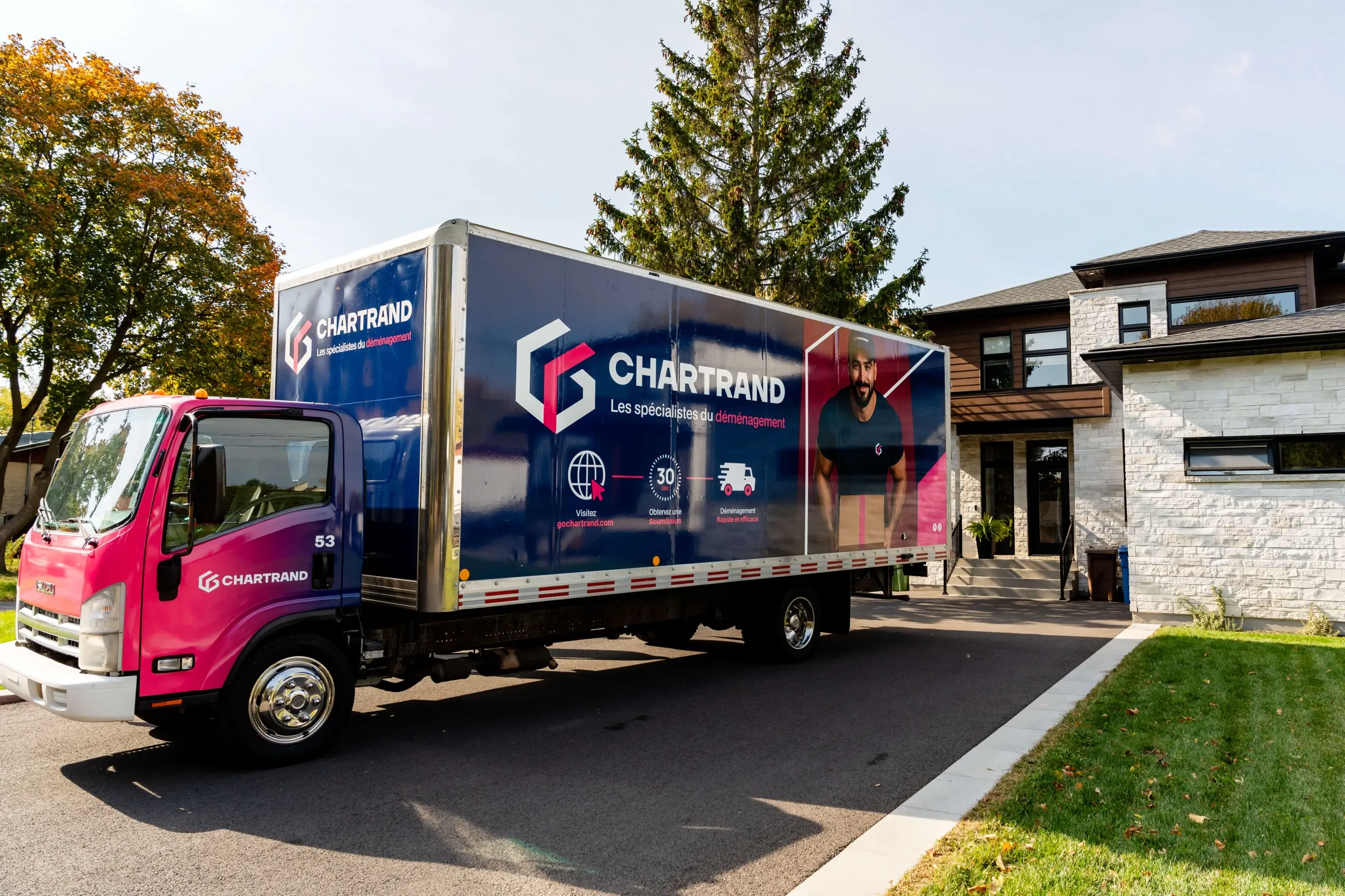 Chartrand truck parked in the driveway of a modern stone house, seen from the side