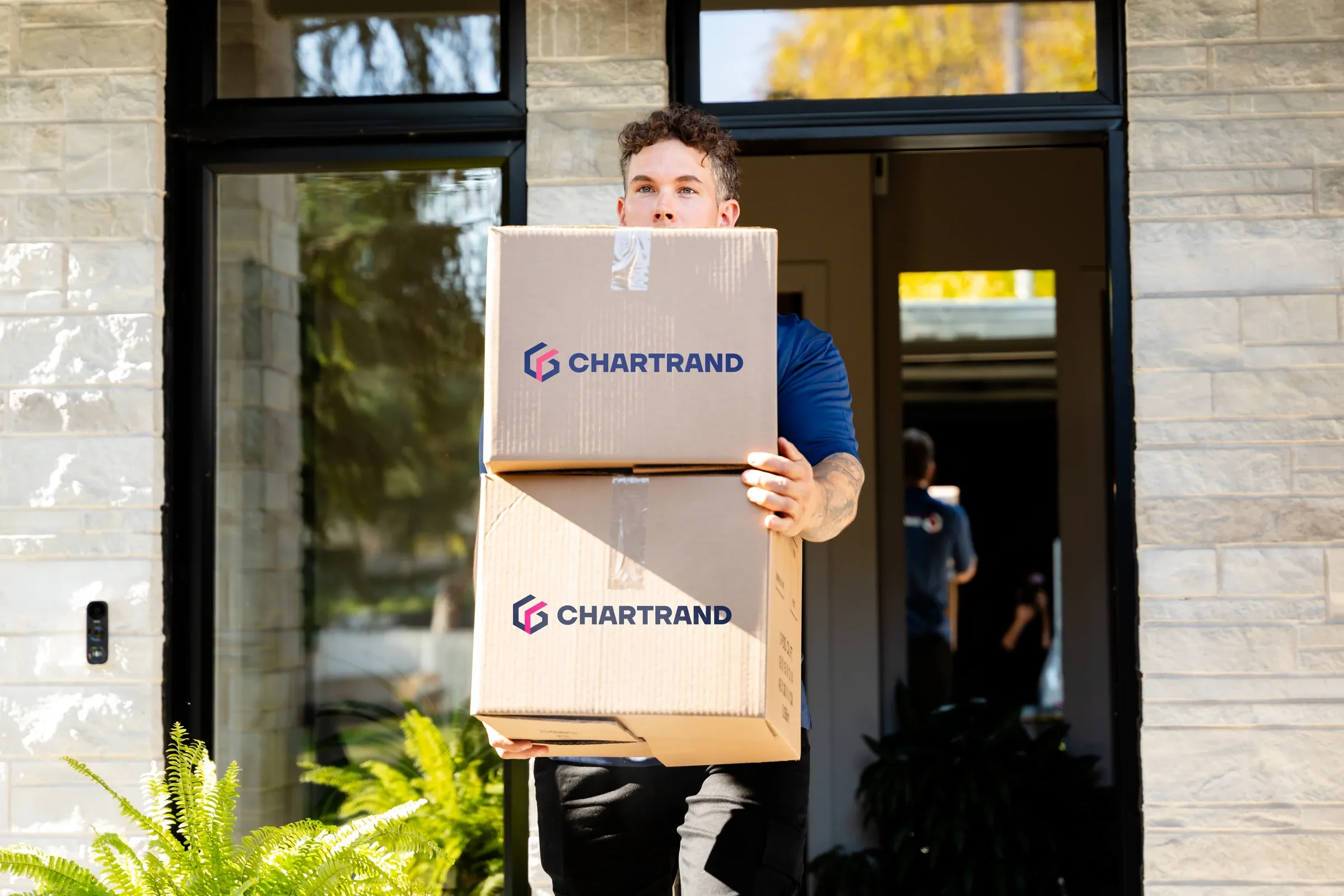 Chartrand mover carrying two boxes at the entrance of a house