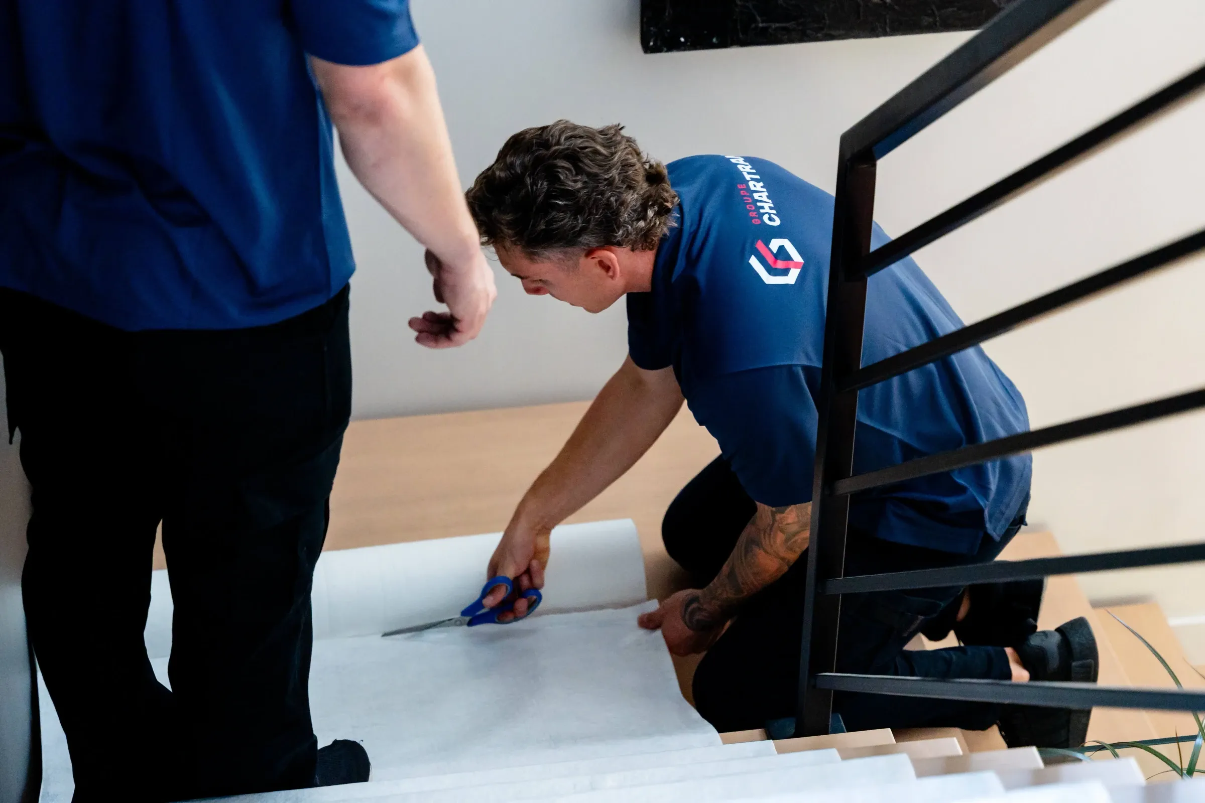 Chartrand mover cutting a protective floor runner at the foot of a staircase